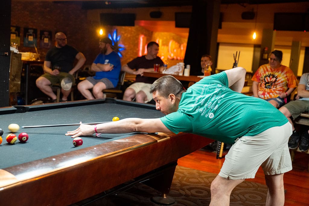 Pool player leaning over table about to make a shot.